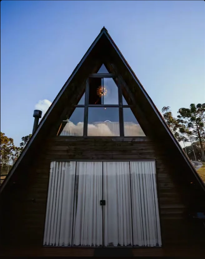 Fachada A-frame do chalé sob céu azul