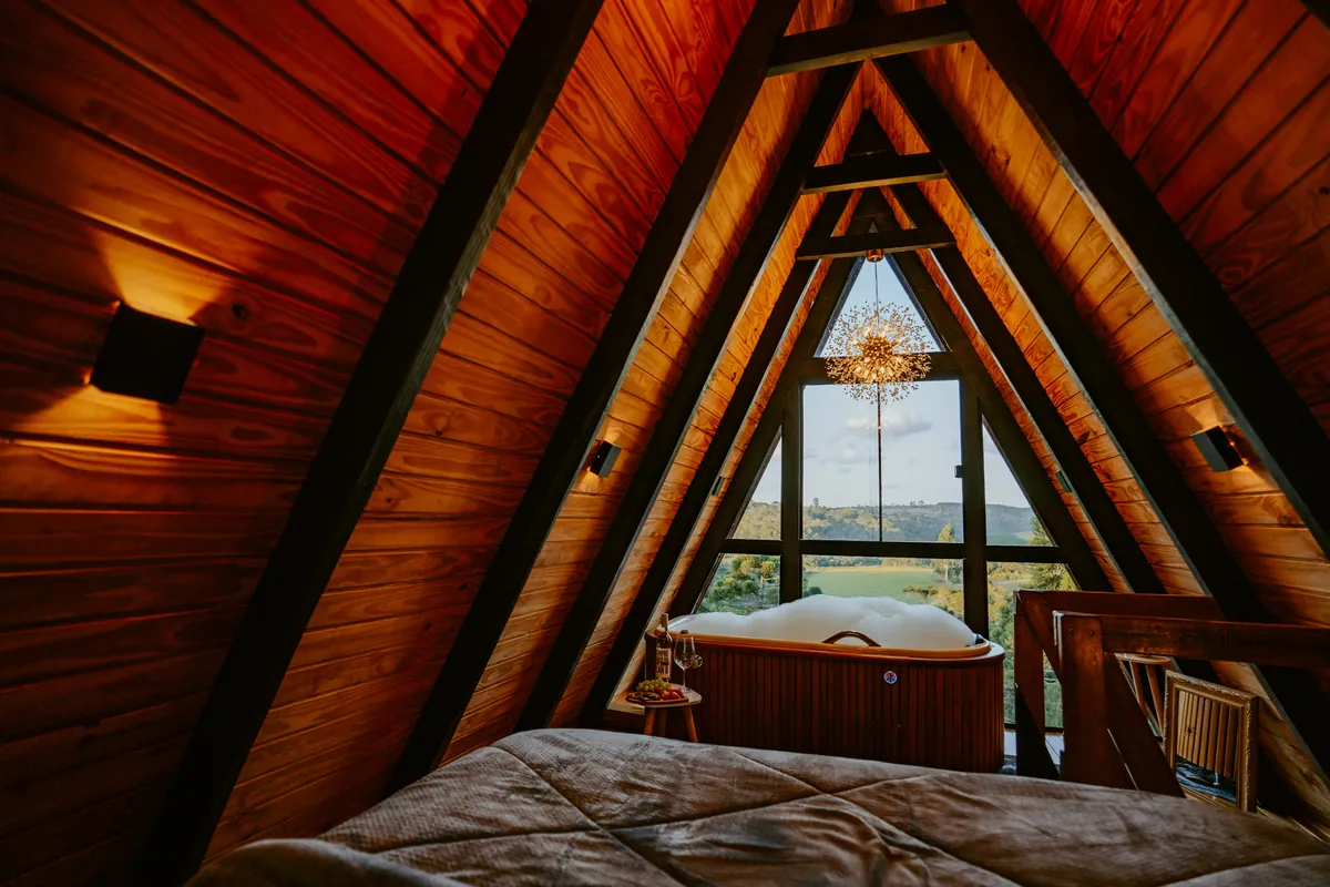 Banheira de hidromassagem no loft, sob o lustre e o vitral triangular